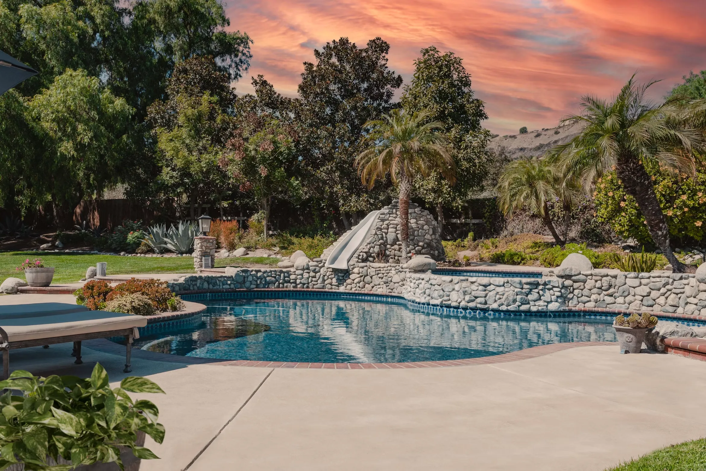 Free-form pool with a stone waterfall at sunset
