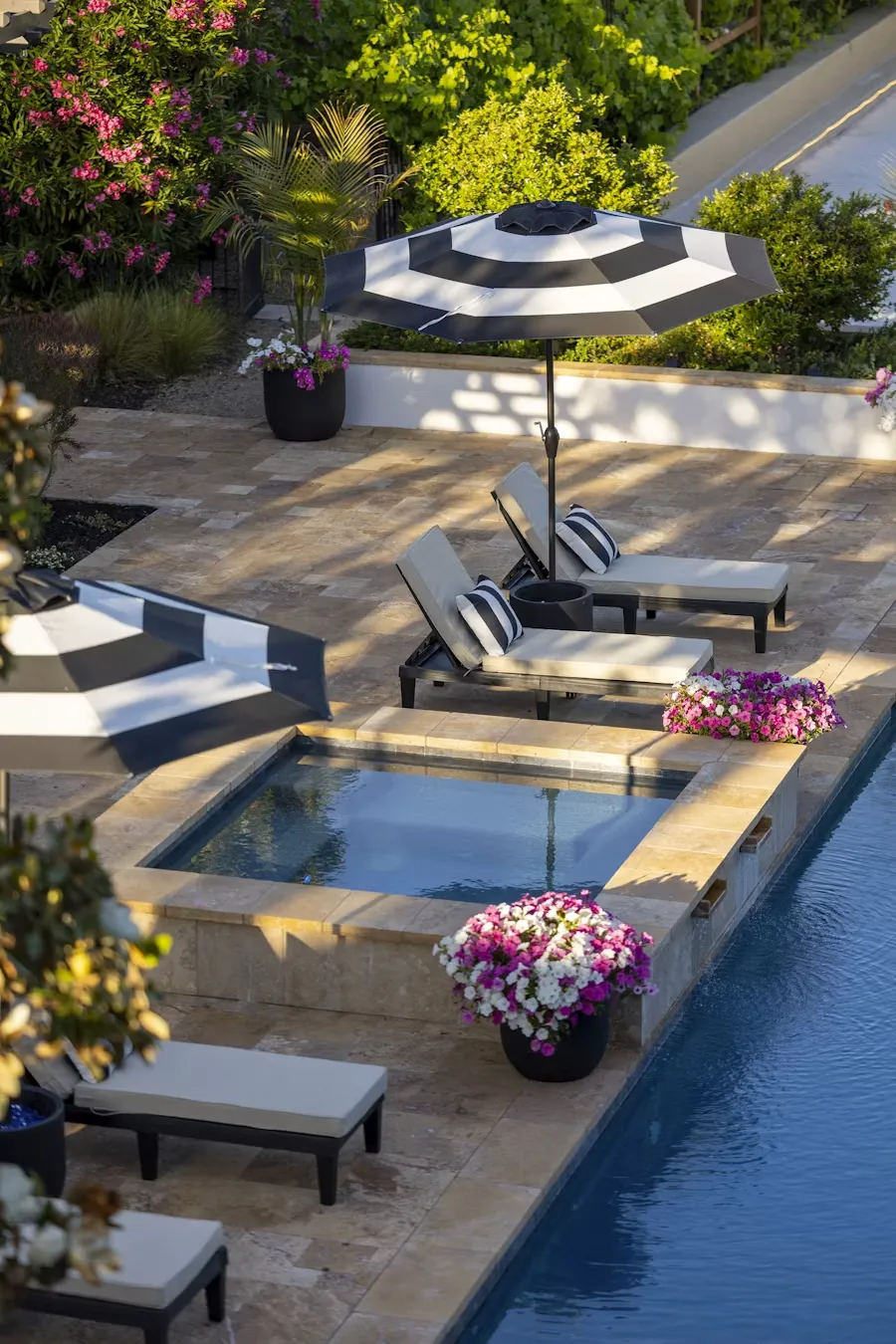 Stone pool terrace with loungers and flowering planters