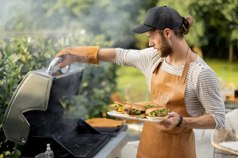 Man serving food from a grill in an outdoor kitchen