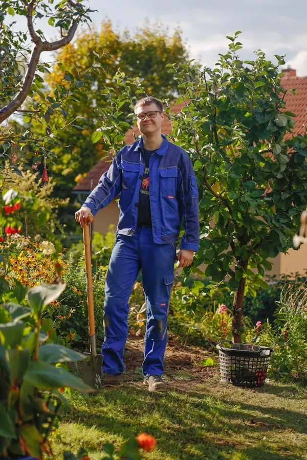 Smiling landscaper leaning on a spade in a garden