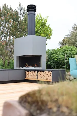 Outdoor fireplace with stacked firewood on a modern patio