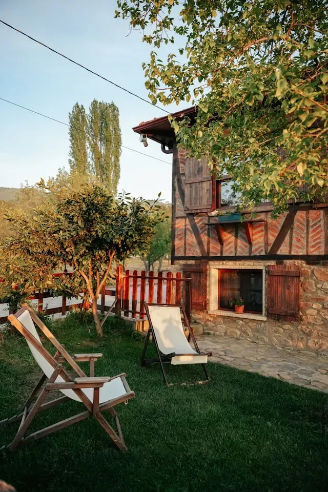 Cottage garden with a green lawn and wooden lounge chairs