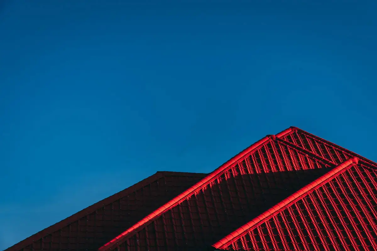 Red metal roof ridgeline against a deep blue evening sky