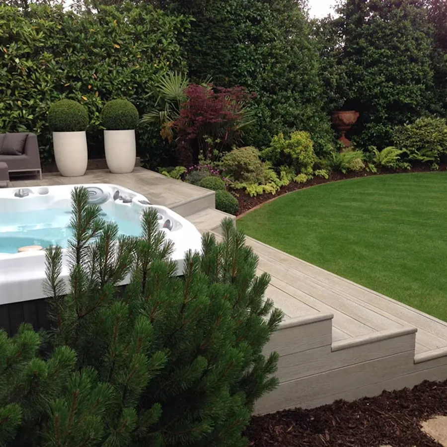 Hot tub surrounded by planters, hedges and colourful shrubs