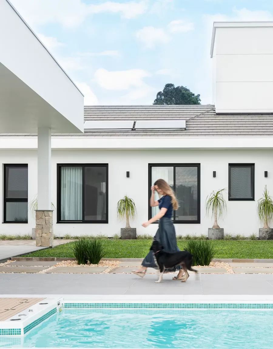 Woman walking past a modern white home with a clean front patio