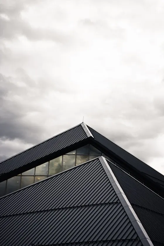 Steep black metal roof against a cloudy sky