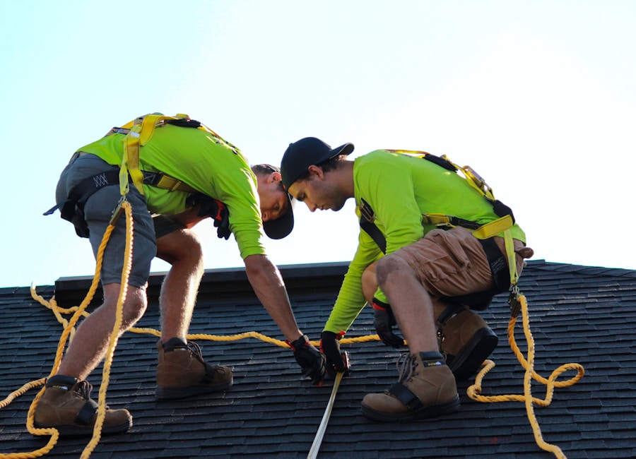 Two roofers in safety harnesses working on a low-slope roof