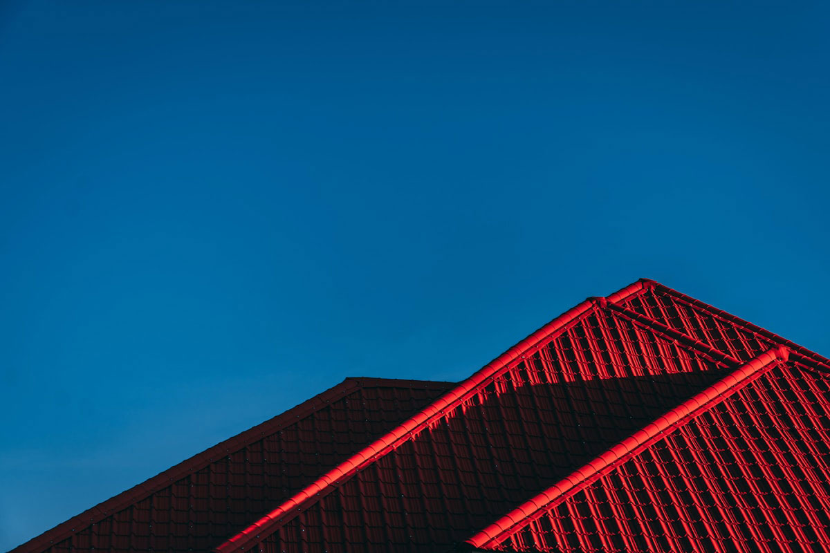 Red metal roof ridgeline against a deep blue evening sky